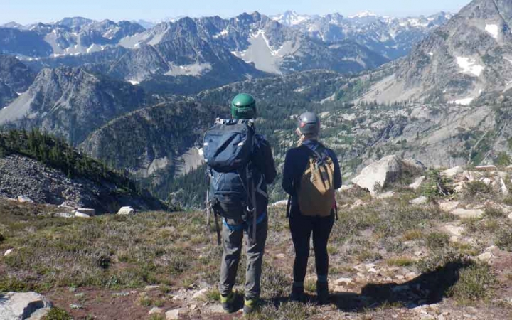 two people overlook a vast mountainous landscape on an outward bound gap year course
